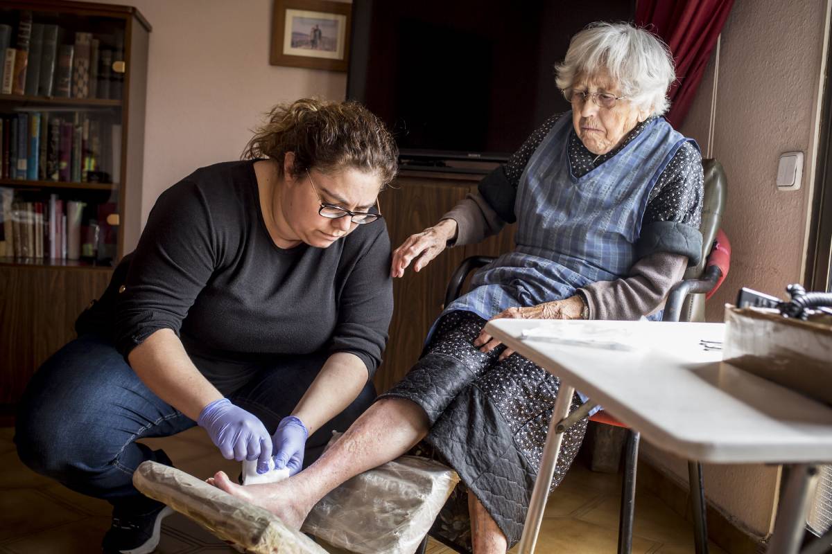 Una enfermera de atención domiciliaria curando una herida. FOTO: Ariadna Creus y Àngel García (Banc Imatges Infermeres).